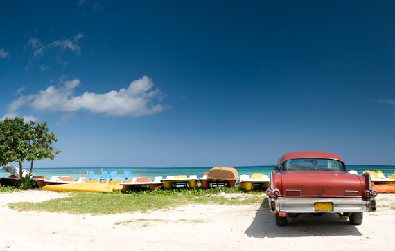 A classic car parked right next to the beach in Cuba, Caribbean.