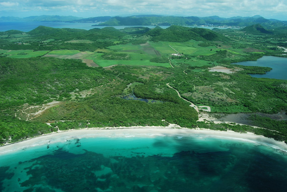 An aerial photograph of the scenic coastline of Martinique with white sand beaches and lush, green, hills.